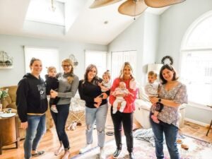 A group of lifelong friends, now moms, holding their babies.